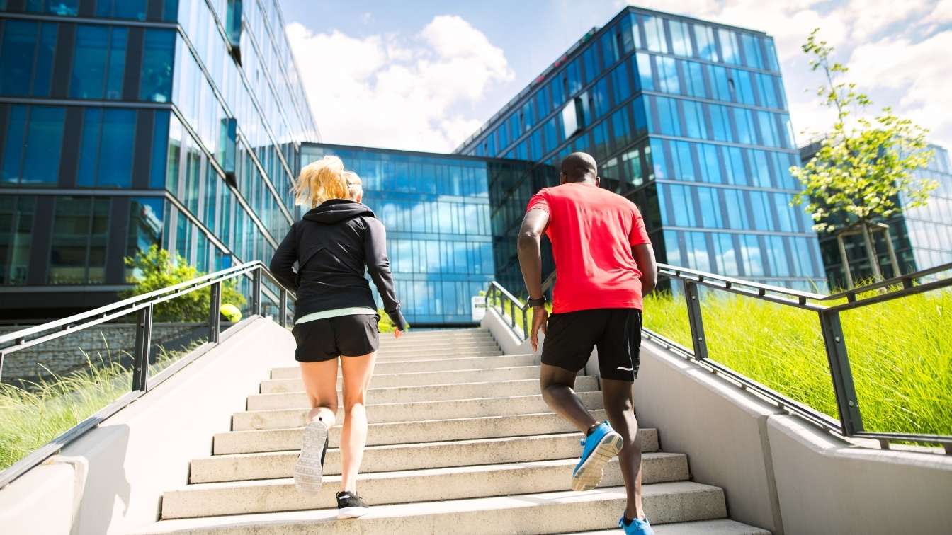 Employees running up steps to office building in athletic clothing