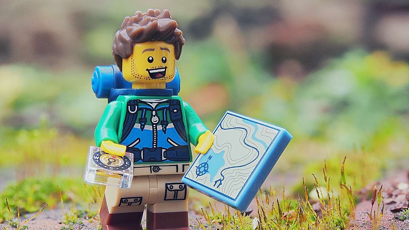 Lego man with compass and map starting on a journey